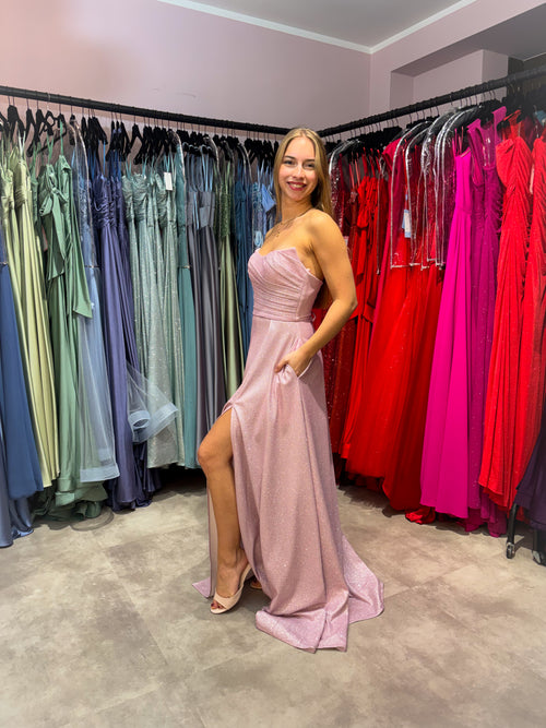 Model trägt ein trägesloses Abiballkleid aus glitzerndem Stoff in Rosa.