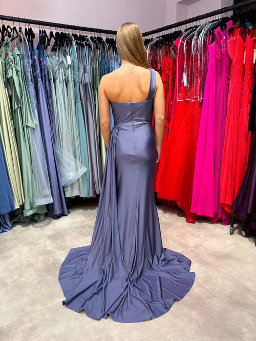 Modell trägt ein jeansblaues One-Shoulder-Kleid, das enganliegend ist und sich besonders gut für Hochzeitsgäste eignet.