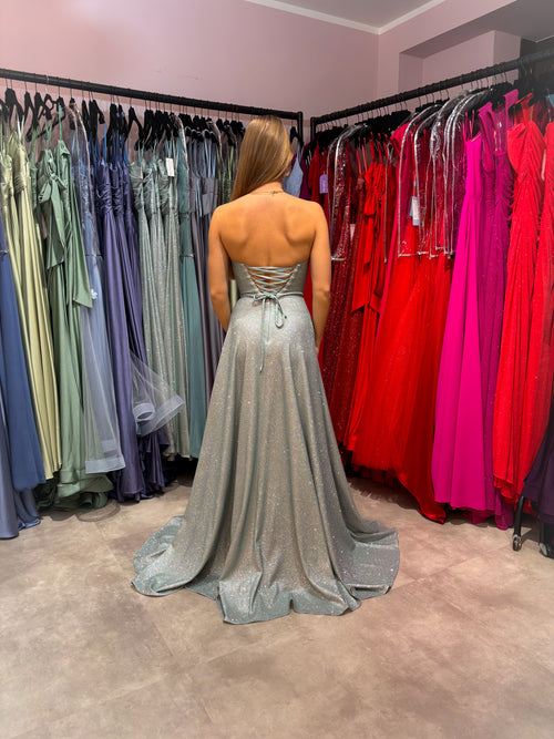 Glitzerndes Abiballkleid in zartem Salbeigrün mit trägerlosem Bustieroberteil und Rock in A-Linie. Das Kleid hat eine Rückenschnürung und einen hohen Beinschlitz sowie seitliche Einschubtaschen.